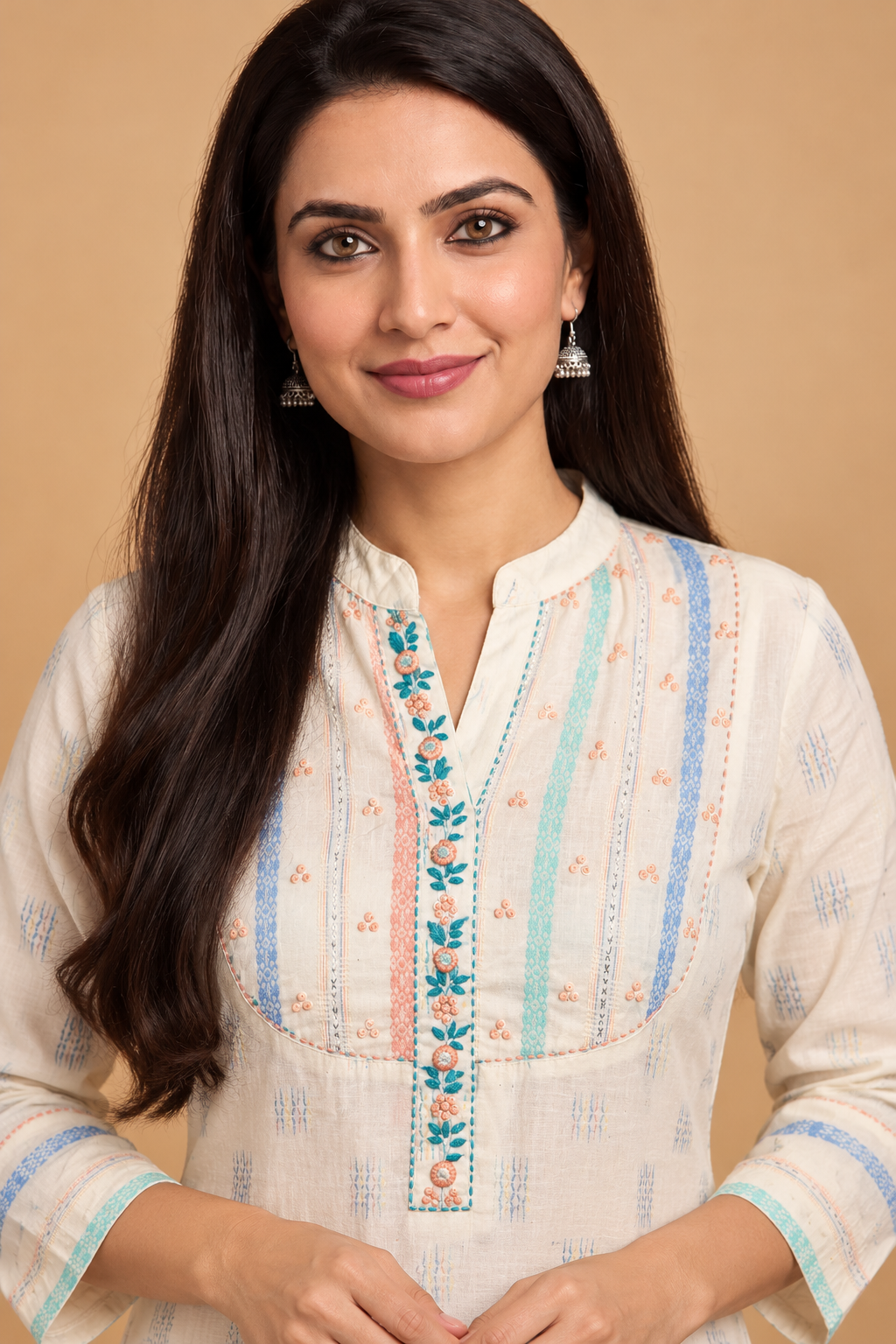 A woman wearing a cream-colored kurta with vertical stripes in light blue and mint green, and a floral embroidered neckline, posed against a solid beige background.